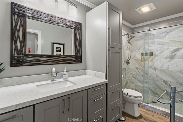 bathroom featuring walk in shower, crown molding, wood-type flooring, toilet, and vanity