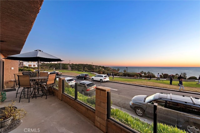 patio terrace at dusk featuring a water view