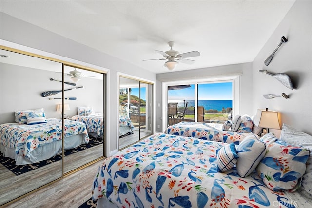 bedroom featuring access to exterior, ceiling fan, multiple closets, and wood finished floors