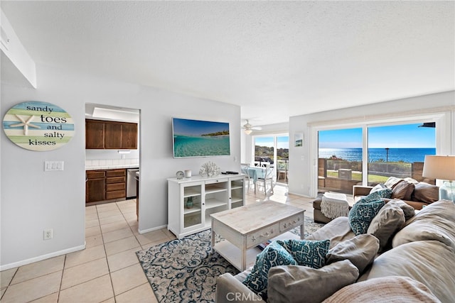 living area with light tile patterned floors, a ceiling fan, baseboards, and a textured ceiling