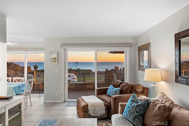 living room featuring light tile patterned floors, a water view, and baseboards