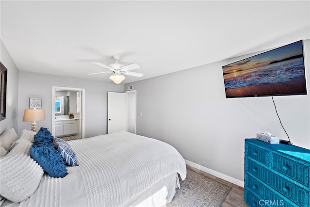 bedroom featuring ceiling fan, baseboards, wood finished floors, and ensuite bathroom