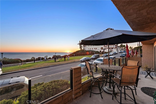 patio terrace at dusk featuring a water view