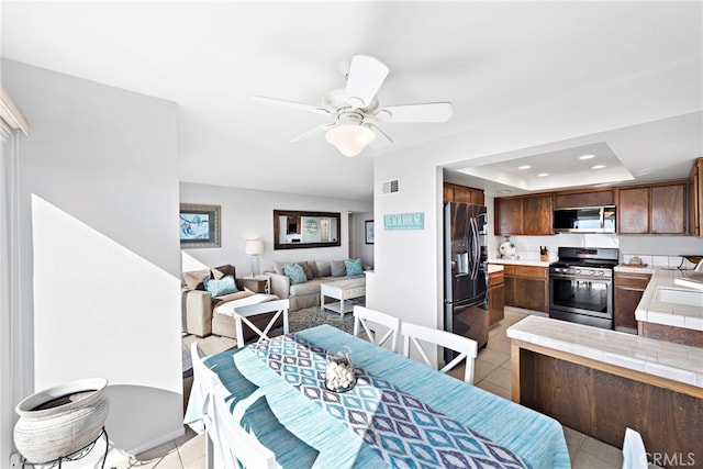 dining room featuring a tray ceiling, light tile patterned floors, recessed lighting, visible vents, and ceiling fan