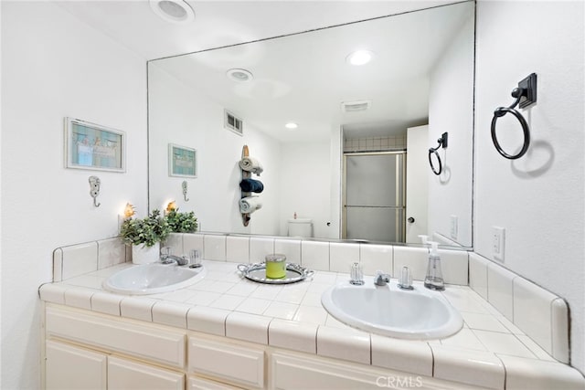 bathroom featuring a stall shower, visible vents, a sink, and double vanity