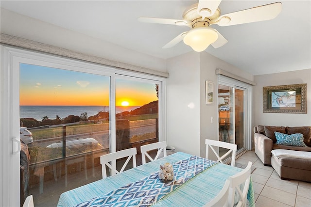 dining area featuring a water view, light tile patterned floors, and a ceiling fan