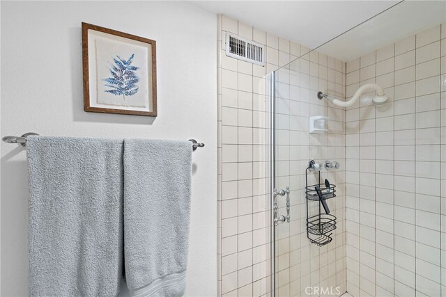 full bathroom featuring tiled shower and visible vents