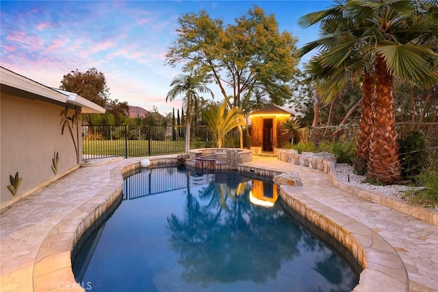 pool at dusk featuring an in ground hot tub