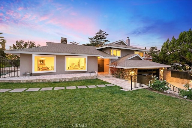 back house at dusk featuring a yard