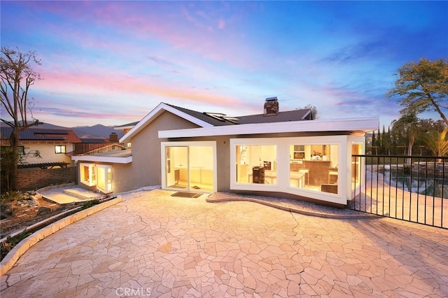 back house at dusk featuring a patio area