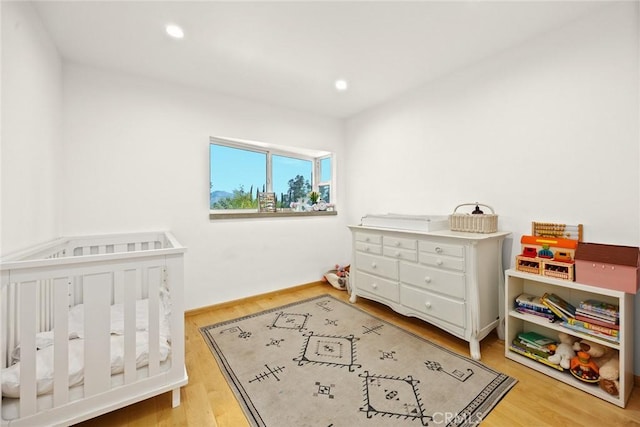 bedroom featuring a crib and light hardwood / wood-style floors