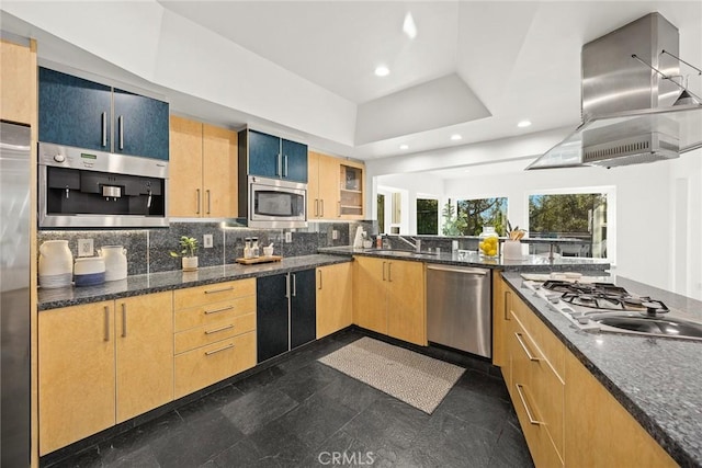 kitchen with sink, dark stone countertops, stainless steel appliances, tasteful backsplash, and island range hood