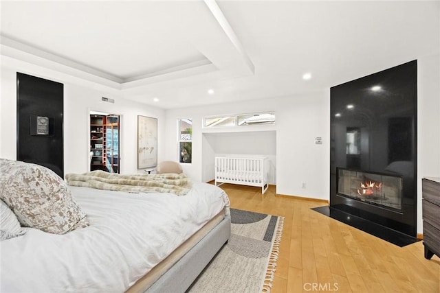 bedroom with a walk in closet, hardwood / wood-style floors, and a tray ceiling