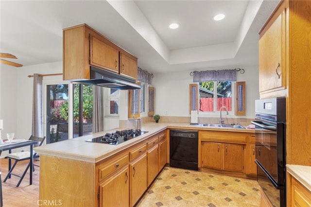 kitchen featuring sink, ceiling fan, kitchen peninsula, a tray ceiling, and black appliances