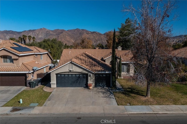 view of front of property featuring a garage, a mountain view, and solar panels