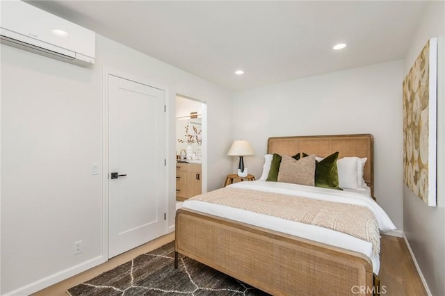 bedroom with wood-type flooring, ensuite bathroom, and a wall mounted AC