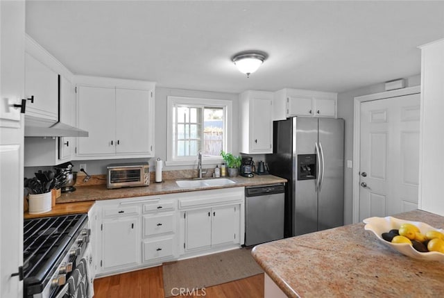 kitchen with white cabinets, sink, stainless steel appliances, and light hardwood / wood-style flooring