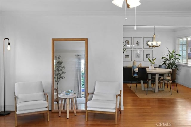 sitting room with a chandelier, hardwood / wood-style flooring, and ornamental molding