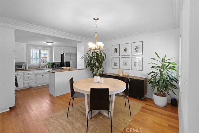 dining room featuring a chandelier, light hardwood / wood-style flooring, ornamental molding, and sink