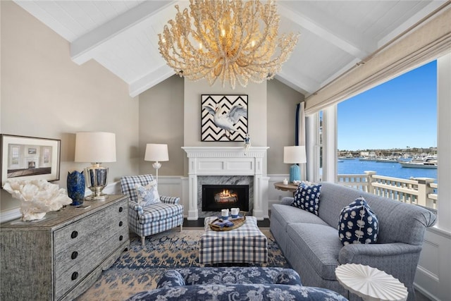 living room with lofted ceiling with beams, a water view, a premium fireplace, and an inviting chandelier