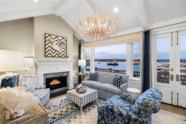 living room with a water view, a notable chandelier, a premium fireplace, hardwood / wood-style floors, and vaulted ceiling with beams