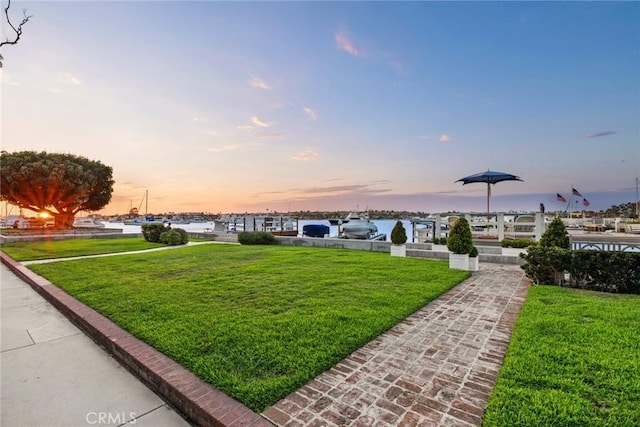 yard at dusk featuring a water view