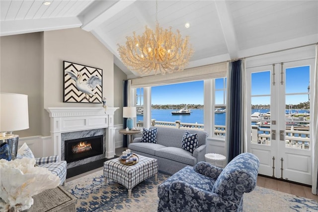 living room with a high end fireplace, lofted ceiling with beams, a water view, hardwood / wood-style flooring, and a notable chandelier