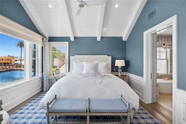 bedroom featuring hardwood / wood-style floors, vaulted ceiling with beams, and connected bathroom