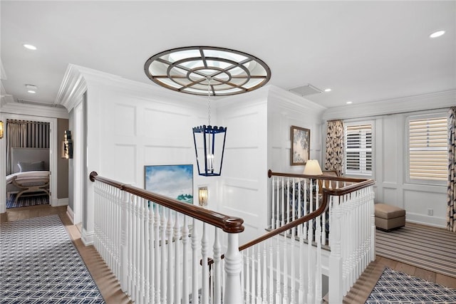 corridor with crown molding, hardwood / wood-style floors, and a notable chandelier