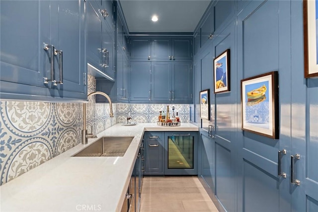 kitchen featuring blue cabinetry, decorative backsplash, sink, and beverage cooler