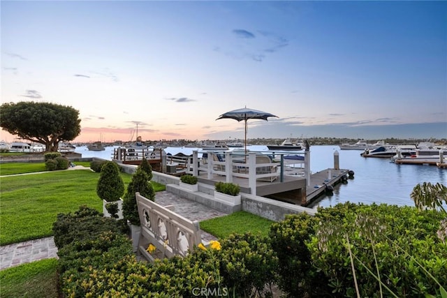 view of dock with a yard and a water view