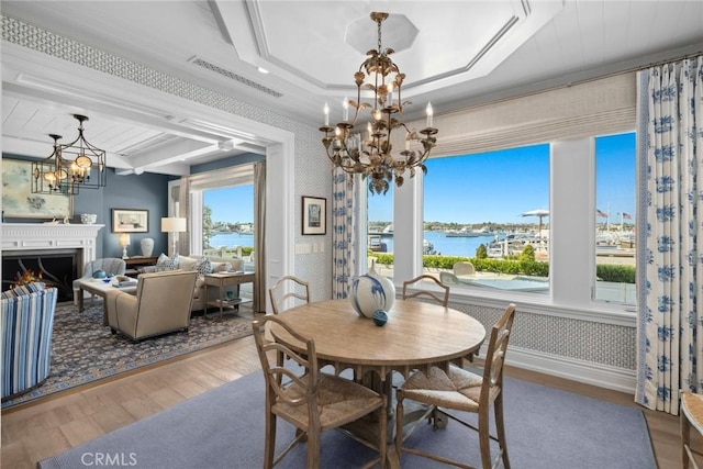 dining space with wood-type flooring, a water view, a raised ceiling, and a wealth of natural light