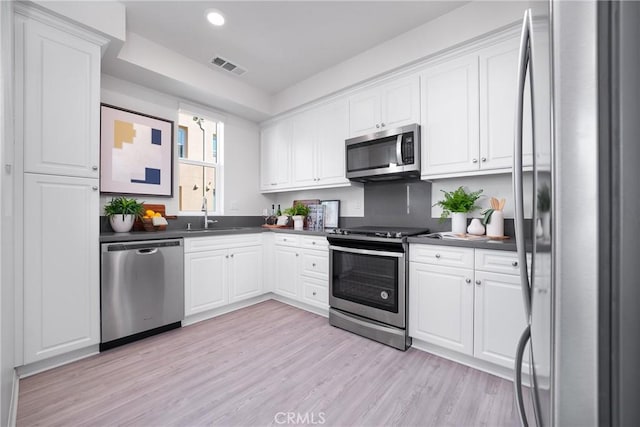 kitchen with sink, white cabinets, stainless steel appliances, and light wood-type flooring