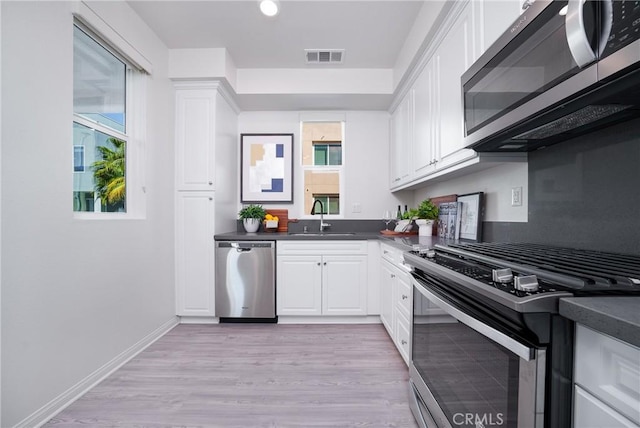 kitchen featuring white cabinets, stainless steel appliances, light hardwood / wood-style floors, and sink