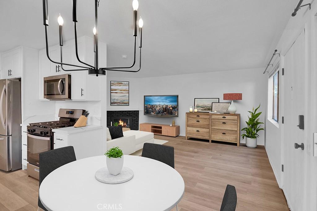 dining area featuring a fireplace, a notable chandelier, and light wood-type flooring