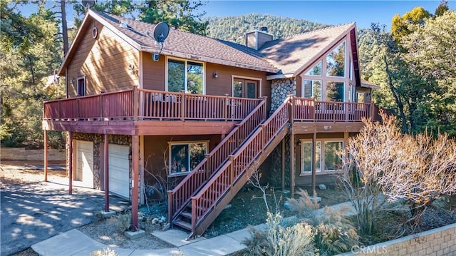 rear view of house featuring a garage and a deck with mountain view