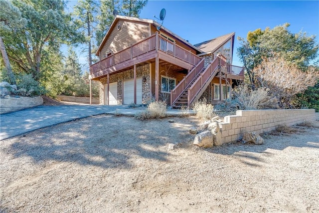 rear view of house featuring a deck and a garage