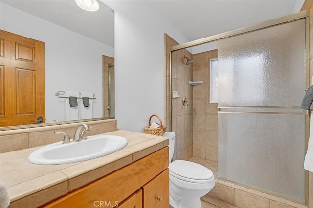 bathroom with toilet, a shower with door, and vanity