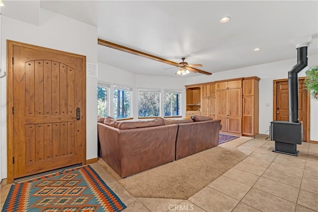 tiled living room featuring ceiling fan and a wood stove