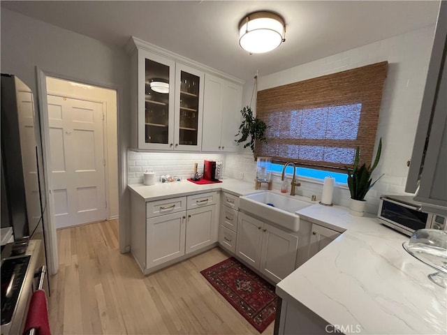 kitchen featuring tasteful backsplash, light stone counters, sink, and light hardwood / wood-style floors