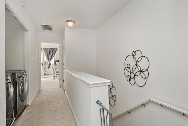 corridor with light colored carpet and independent washer and dryer