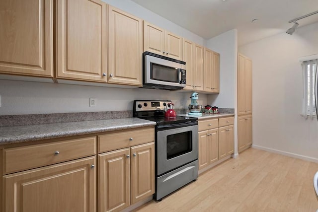 kitchen featuring track lighting, light brown cabinetry, light hardwood / wood-style floors, and appliances with stainless steel finishes