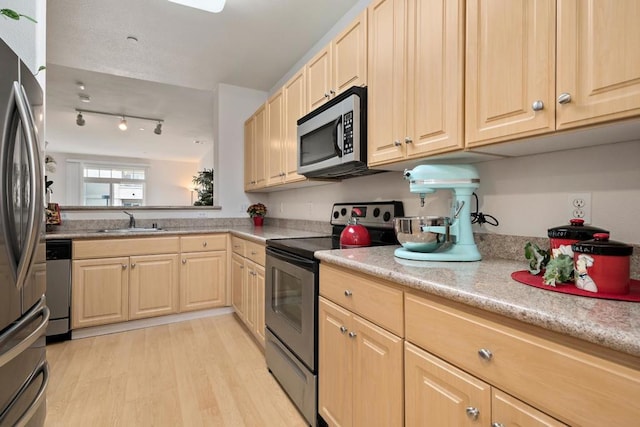 kitchen with appliances with stainless steel finishes, light hardwood / wood-style flooring, light brown cabinets, and sink