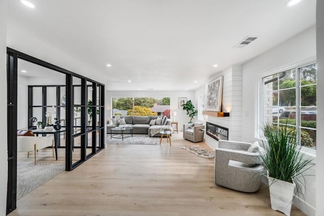 living room with a large fireplace and light hardwood / wood-style flooring