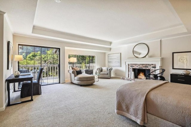 carpeted bedroom with a tray ceiling, a fireplace, and access to outside