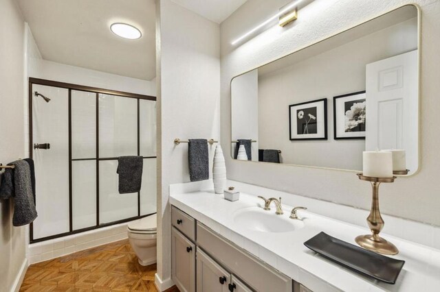 bathroom featuring an enclosed shower, parquet floors, vanity, and toilet