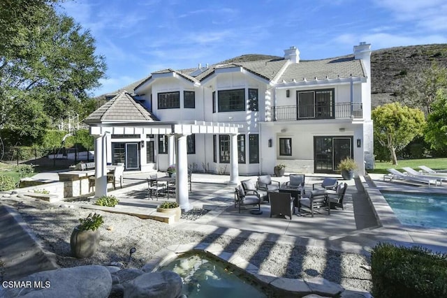 back of house featuring a balcony and a patio