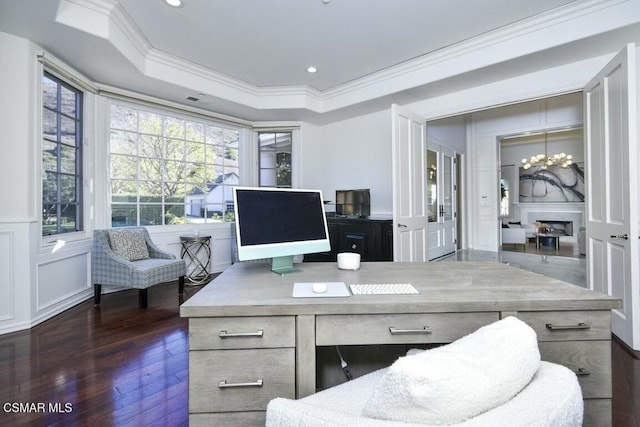 home office with dark wood-type flooring, a tray ceiling, crown molding, a fireplace, and built in desk