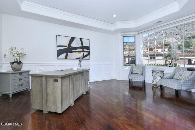 sitting room with dark wood-type flooring, a raised ceiling, and ornamental molding