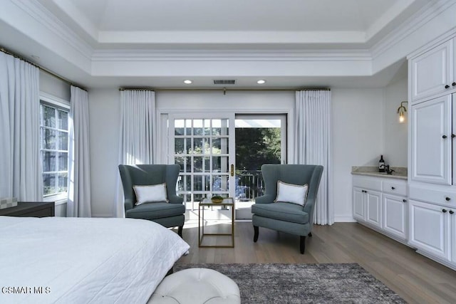 bedroom with ornamental molding, a raised ceiling, and hardwood / wood-style flooring